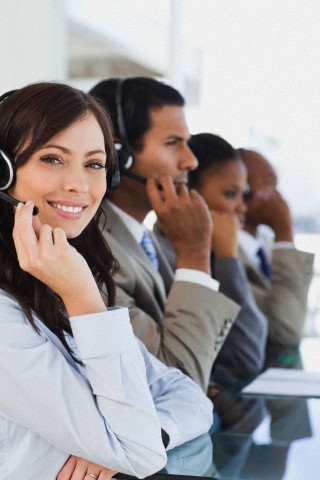 Smiling call centre agent looking at the camera while working hard
